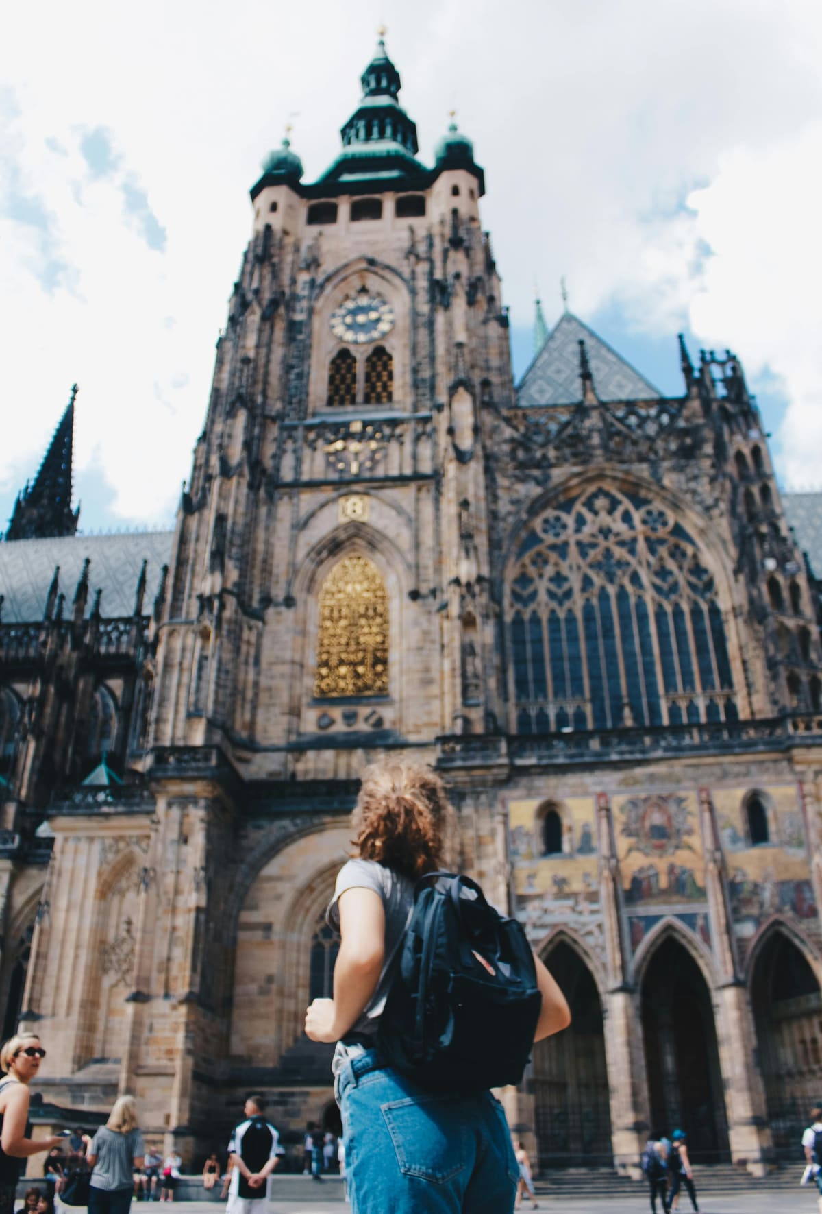 A traveler with a backpack looking up at a gothic cathedral